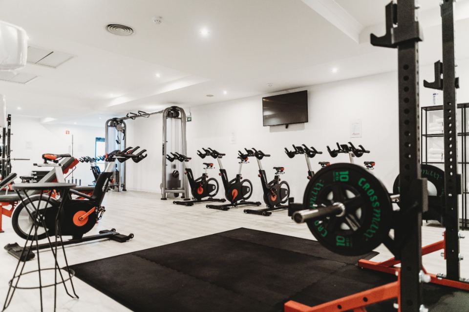 A bright training floor with racks, bikes and platforms